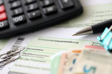 Kalem ve avrupa para faturalarıyla birlikte Alman gelir vergisi iadesi formu muhasebeci masasına yakın duruyor. Almanya 'daki vergi mükellefleri, vergi ödemek için ana para birimi olarak avro para kullanıyorlar