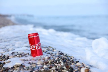 ANTALYA, TURKEY - 18 Mayıs 2021: Orijinal Coca Cola kırmızı teneke kutu deniz kıyısına yakın küçük yuvarlak çakıl taşları üzerinde yatar. Türk plaj taşları üzerinde Coca-Cola