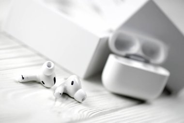 KHARKIV, UKRAINE - JANUARY 27, 2021: Apple AirPods Pro on a white background. Wireless headphones with charging case and a box. Apple Inc. is an American technology company headquartered in California