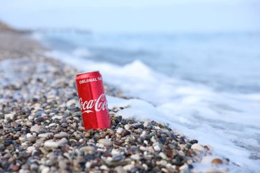 ANTALYA, TURKEY - 18 Mayıs 2021: Orijinal Coca Cola kırmızı teneke kutu deniz kıyısına yakın küçük yuvarlak çakıl taşları üzerinde yatar. Türk plaj taşları üzerinde Coca-Cola