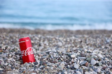 ANTALYA, TURKEY - 18 Mayıs 2021: Orijinal Coca Cola kırmızı teneke kutu deniz kıyısına yakın küçük yuvarlak çakıl taşları üzerinde yatar. Türk plaj taşları üzerinde Coca-Cola