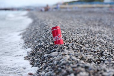 ANTALYA, TURKEY - 18 Mayıs 2021: Orijinal Coca Cola kırmızı teneke kutu deniz kıyısına yakın küçük yuvarlak çakıl taşları üzerinde yatar. Türk plaj taşları üzerinde Coca-Cola