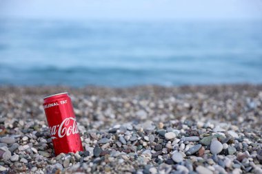 ANTALYA, TURKEY - 18 Mayıs 2021: Orijinal Coca Cola kırmızı teneke kutu deniz kıyısına yakın küçük yuvarlak çakıl taşları üzerinde yatar. Türk plaj taşları üzerinde Coca-Cola