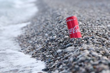 ANTALYA, TURKEY - 18 Mayıs 2021: Orijinal Coca Cola kırmızı teneke kutu deniz kıyısına yakın küçük yuvarlak çakıl taşları üzerinde yatar. Türk plaj taşları üzerinde Coca-Cola