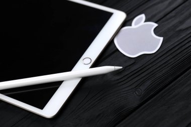 KHARKIV, UKRAINE - 27 Ocak 2021: Gıcır gıcır Apple iPad ve Apple kalem ve siyah arka planda gri şirket logosu. Apple Inc. merkezi Kaliforniya 'da bulunan bir Amerikan teknoloji şirketidir.