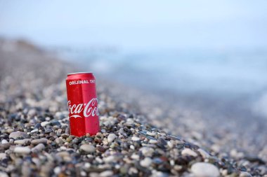ANTALYA, TURKEY - 18 Mayıs 2021: Orijinal Coca Cola kırmızı teneke kutu deniz kıyısına yakın küçük yuvarlak çakıl taşları üzerinde yatar. Türk plaj taşları üzerinde Coca-Cola