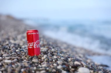 ANTALYA, TURKEY - 18 Mayıs 2021: Orijinal Coca Cola kırmızı teneke kutu deniz kıyısına yakın küçük yuvarlak çakıl taşları üzerinde yatar. Türk plaj taşları üzerinde Coca-Cola
