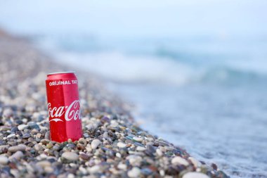ANTALYA, TURKEY - 18 Mayıs 2021: Orijinal Coca Cola kırmızı teneke kutu deniz kıyısına yakın küçük yuvarlak çakıl taşları üzerinde yatar. Türk plaj taşları üzerinde Coca-Cola