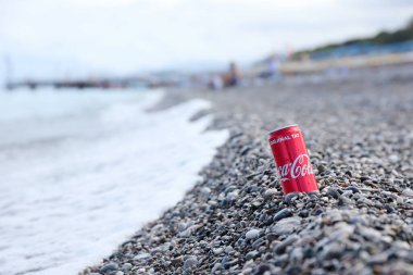 ANTALYA, TURKEY - 18 Mayıs 2021: Orijinal Coca Cola kırmızı teneke kutu deniz kıyısına yakın küçük yuvarlak çakıl taşları üzerinde yatar. Türk plaj taşları üzerinde Coca-Cola