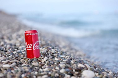 ANTALYA, TURKEY - 18 Mayıs 2021: Orijinal Coca Cola kırmızı teneke kutu deniz kıyısına yakın küçük yuvarlak çakıl taşları üzerinde yatar. Türk plaj taşları üzerinde Coca-Cola