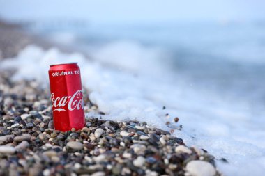 ANTALYA, TURKEY - 18 Mayıs 2021: Orijinal Coca Cola kırmızı teneke kutu deniz kıyısına yakın küçük yuvarlak çakıl taşları üzerinde yatar. Türk plaj taşları üzerinde Coca-Cola