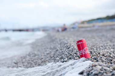 ANTALYA, TURKEY - 18 Mayıs 2021: Orijinal Coca Cola kırmızı teneke kutu deniz kıyısına yakın küçük yuvarlak çakıl taşları üzerinde yatar. Türk plaj taşları üzerinde Coca-Cola
