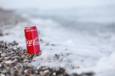 ANTALYA, TURKEY - 18 Mayıs 2021: Orijinal Coca Cola kırmızı teneke kutu deniz kıyısına yakın küçük yuvarlak çakıl taşları üzerinde yatar. Türk plaj taşları üzerinde Coca-Cola