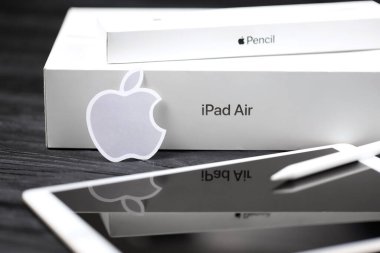 KHARKIV, UKRAINE - JANUARY 27, 2021: Brand new Apple iPad and Apple Pencil and gray company logo on black background. Apple Inc. is an American technology company headquartered in California