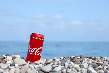 ANTALYA, TURKEY - 18 Mayıs 2021: Orijinal Coca Cola kırmızı teneke kutu deniz kıyısına yakın küçük yuvarlak çakıl taşları üzerinde yatar. Türk plaj taşları üzerinde Coca-Cola