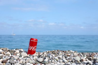 ANTALYA, TURKEY - 18 Mayıs 2021: Orijinal Coca Cola kırmızı teneke kutu deniz kıyısına yakın küçük yuvarlak çakıl taşları üzerinde yatar. Türk plaj taşları üzerinde Coca-Cola