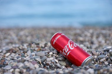 ANTALYA, TURKEY - 18 Mayıs 2021: Orijinal Coca Cola kırmızı teneke kutu deniz kıyısına yakın küçük yuvarlak çakıl taşları üzerinde yatar. Türk plaj taşları üzerinde Coca-Cola