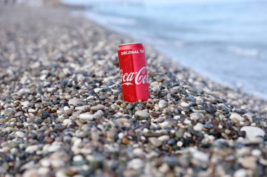 ANTALYA, TURKEY - 18 Mayıs 2021: Orijinal Coca Cola kırmızı teneke kutu deniz kıyısına yakın küçük yuvarlak çakıl taşları üzerinde yatar. Türk plaj taşları üzerinde Coca-Cola