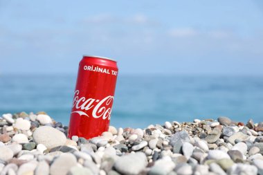 ANTALYA, TURKEY - 18 Mayıs 2021: Orijinal Coca Cola kırmızı teneke kutu deniz kıyısına yakın küçük yuvarlak çakıl taşları üzerinde yatar. Türk plaj taşları üzerinde Coca-Cola