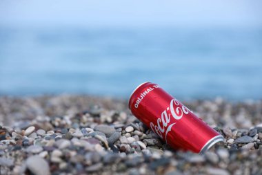 ANTALYA, TURKEY - 18 Mayıs 2021: Orijinal Coca Cola kırmızı teneke kutu deniz kıyısına yakın küçük yuvarlak çakıl taşları üzerinde yatar. Türk plaj taşları üzerinde Coca-Cola