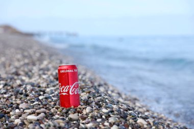 ANTALYA, TURKEY - 18 Mayıs 2021: Orijinal Coca Cola kırmızı teneke kutu deniz kıyısına yakın küçük yuvarlak çakıl taşları üzerinde yatar. Türk plaj taşları üzerinde Coca-Cola