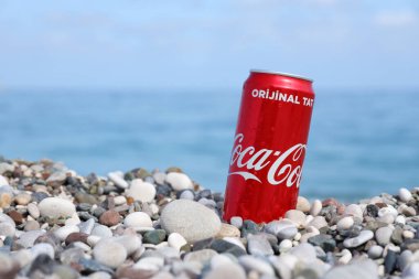 ANTALYA, TURKEY - 18 Mayıs 2021: Orijinal Coca Cola kırmızı teneke kutu deniz kıyısına yakın küçük yuvarlak çakıl taşları üzerinde yatar. Türk plaj taşları üzerinde Coca-Cola