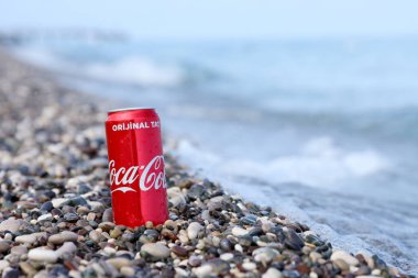 ANTALYA, TURKEY - 18 Mayıs 2021: Orijinal Coca Cola kırmızı teneke kutu deniz kıyısına yakın küçük yuvarlak çakıl taşları üzerinde yatar. Türk plaj taşları üzerinde Coca-Cola