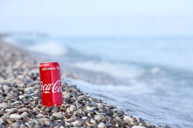 ANTALYA, TURKEY - 18 Mayıs 2021: Orijinal Coca Cola kırmızı teneke kutu deniz kıyısına yakın küçük yuvarlak çakıl taşları üzerinde yatar. Türk plaj taşları üzerinde Coca-Cola