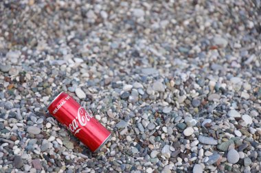 ANTALYA, TURKEY - 18 Mayıs 2021: Orijinal Coca Cola kırmızı teneke kutu deniz kıyısına yakın küçük yuvarlak çakıl taşları üzerinde yatar. Türk plaj taşları üzerinde Coca-Cola