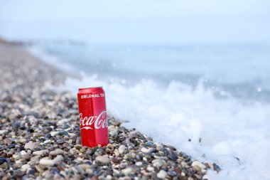 ANTALYA, TURKEY - 18 Mayıs 2021: Orijinal Coca Cola kırmızı teneke kutu deniz kıyısına yakın küçük yuvarlak çakıl taşları üzerinde yatar. Türk plaj taşları üzerinde Coca-Cola