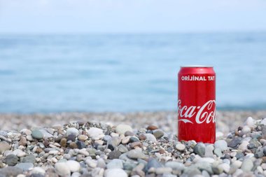 ANTALYA, TURKEY - 18 Mayıs 2021: Orijinal Coca Cola kırmızı teneke kutu deniz kıyısına yakın küçük yuvarlak çakıl taşları üzerinde yatar. Türk plaj taşları üzerinde Coca-Cola