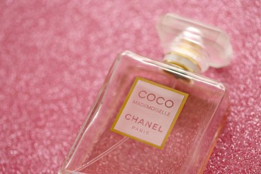 TERNOPIL, UKRAINE - SEPTEMBER 2, 2022 Coco Mademoiselle Chanel Paris worldwide famous french perfume bottle on shiny glitter background in purple and pink colors