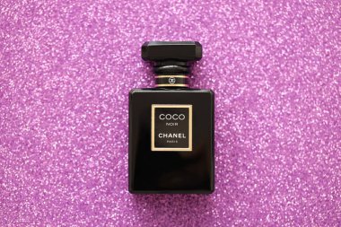 TERNOPIL, UKRAINE - SEPTEMBER 2, 2022 Coco Noir Chanel Paris worldwide famous french perfume black bottle on shiny glitter background in purple and pink colors