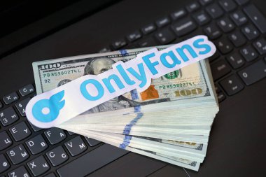 TERNOPIL, UKRAINE - SEPTEMBER 6, 2022 Onlyfans paper logotype on bunch of US dollar bills lies on black laptop keyboard buttons