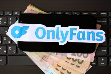 TERNOPIL, UKRAINE - SEPTEMBER 6, 2022 Onlyfans paper logotype on bunch of ukrainian hryvnias bills lies on black laptop keyboard buttons