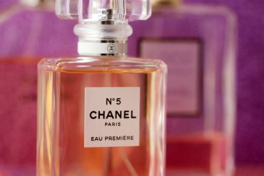 TERNOPIL, UKRAINE - SEPTEMBER 2, 2022 Chanel Number 5 Eau Premiere worldwide famous french perfume bottle among other perfumes on shiny glitter background in purple and pink colors
