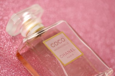 TERNOPIL, UKRAINE - SEPTEMBER 2, 2022 Coco Mademoiselle Chanel Paris worldwide famous french perfume bottle on shiny glitter background in purple and pink colors
