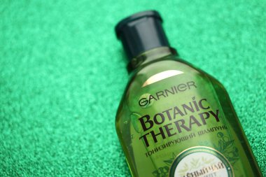 TERNOPIL, UKRAINE - SEPTEMBER 2, 2022 Bottle of Garnier Botanic Therapy Green Tea Shampoo on green glitter background surface