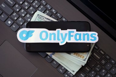 TERNOPIL, UKRAINE - SEPTEMBER 6, 2022 Onlyfans paper logotype on bunch of US dollar bills lies on black laptop keyboard buttons