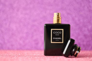 TERNOPIL, UKRAINE - SEPTEMBER 2, 2022 Coco Noir Chanel Paris worldwide famous french perfume black bottle on shiny glitter background in purple and pink colors