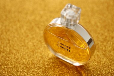 TERNOPIL, UKRAINE - SEPTEMBER 2, 2022 Chanel Chance worldwide famous french perfume bottle on shiny glitter background in golden and yellow colors