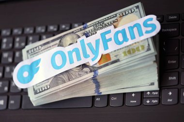 TERNOPIL, UKRAINE - SEPTEMBER 6, 2022 Onlyfans paper logotype on bunch of US dollar bills lies on black laptop keyboard buttons