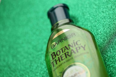 TERNOPIL, UKRAINE - SEPTEMBER 2, 2022 Bottle of Garnier Botanic Therapy Green Tea Shampoo on green glitter background surface
