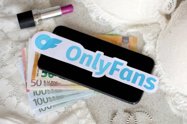 TERNOPIL, UKRAINE - SEPTEMBER 6, 2022 Onlyfans paper logotype among lipstick, earrings and women lingerie close to bunch of few euro bills