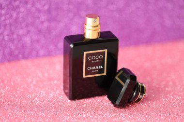 TERNOPIL, UKRAINE - SEPTEMBER 2, 2022 Coco Noir Chanel Paris worldwide famous french perfume black bottle on shiny glitter background in purple and pink colors
