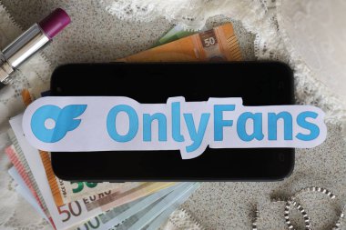 TERNOPIL, UKRAINE - SEPTEMBER 6, 2022 Onlyfans paper logotype among lipstick, earrings and women lingerie close to bunch of few euro bills