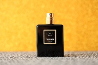 TERNOPIL, UKRAINE - SEPTEMBER 2, 2022 Coco Noir Chanel Paris worldwide famous french perfume black bottle on shiny glitter background in golden and yellow colors