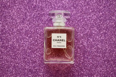 TERNOPIL, UKRAINE - SEPTEMBER 2, 2022 Chanel Number 5 Eau Premiere worldwide famous french perfume bottle on shiny glitter background in pink and purple colors