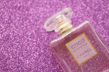 TERNOPIL, UKRAINE - SEPTEMBER 2, 2022 Coco Mademoiselle Chanel Paris worldwide famous french perfume bottle on shiny glitter background in purple and pink colors