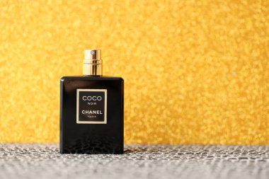 TERNOPIL, UKRAINE - SEPTEMBER 2, 2022 Coco Noir Chanel Paris worldwide famous french perfume black bottle on shiny glitter background in golden and yellow colors